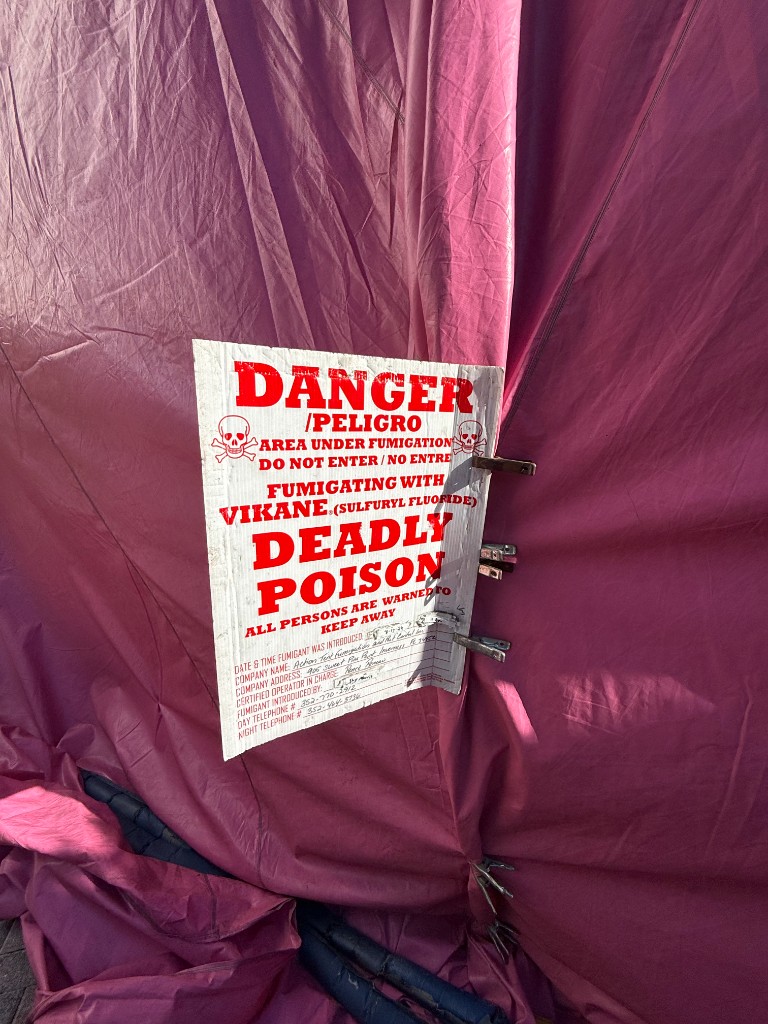 DANGER fumigation warning sign clipped to sealed tarps during a tent fumigation job
